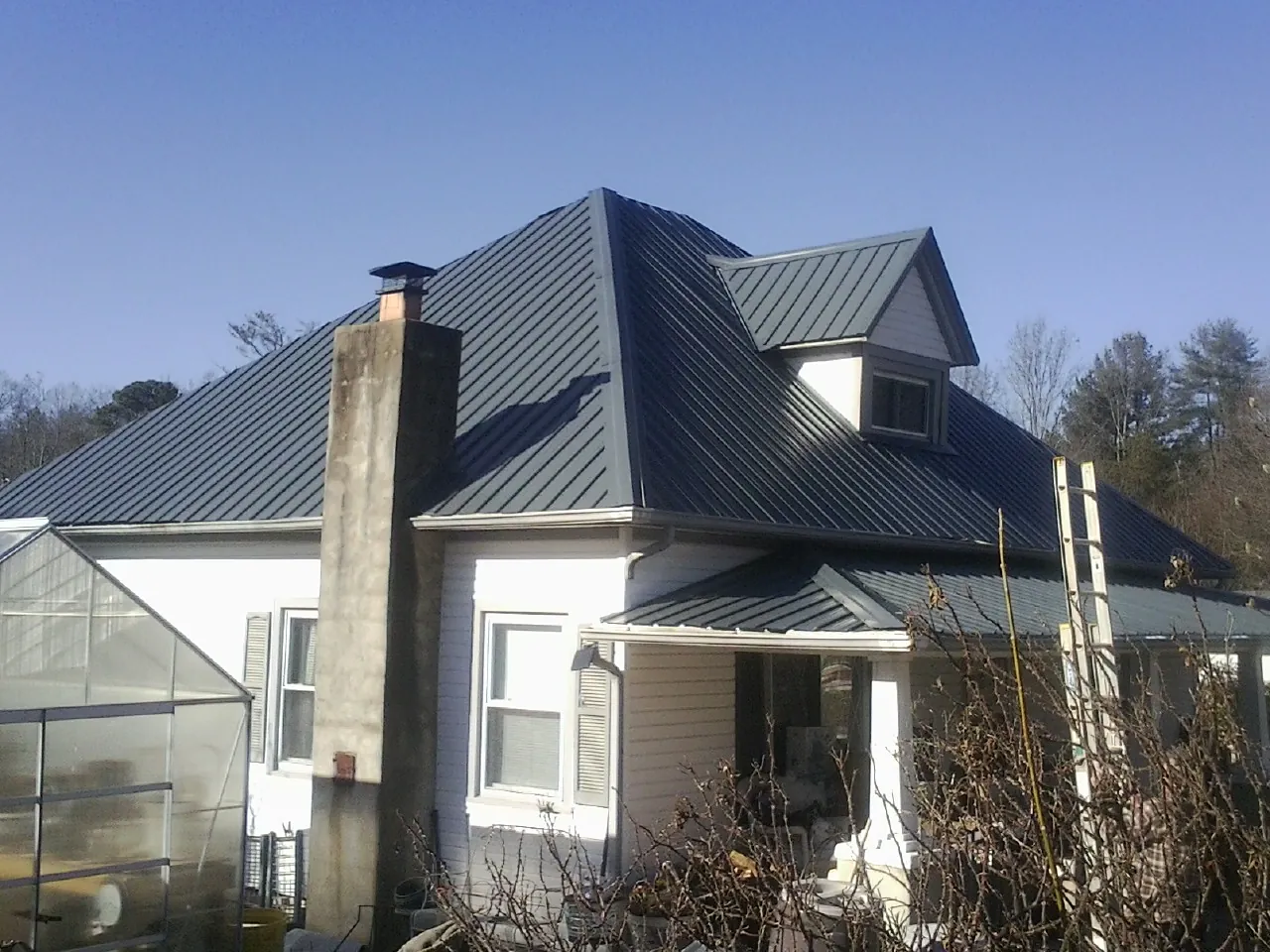 Dark blue standing seam metal roof on a white farmhouse with dormer — Slate & Tile Roof Repair by Roofing Brothers in Panguitch