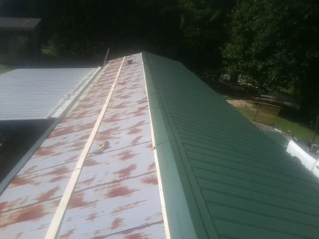 Old rusted panels beside newly installed green metal roofing — Wind Damage Roof Repair by Roofing Brothers in Panguitch