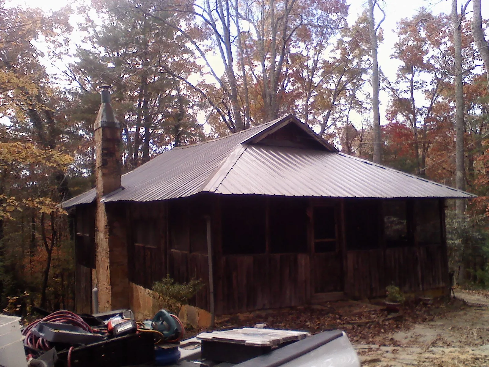 Brown metal hip roof on an old cabin with a stone chimney in Panguitch