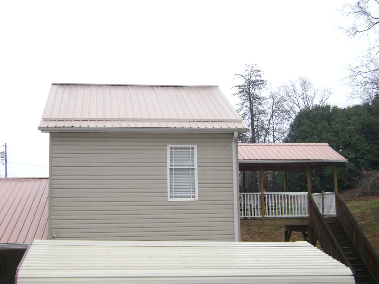 Tan metal roofs on a two story addition and attached porch, from a Roof Replacement job in Panguitch