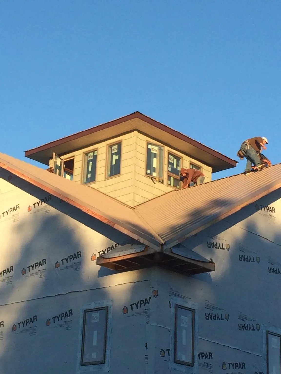 Roofers working around a rooftop cupola on a new metal roof at sunset — Roof Waterproofing in Panguitch by Roofing Brothers